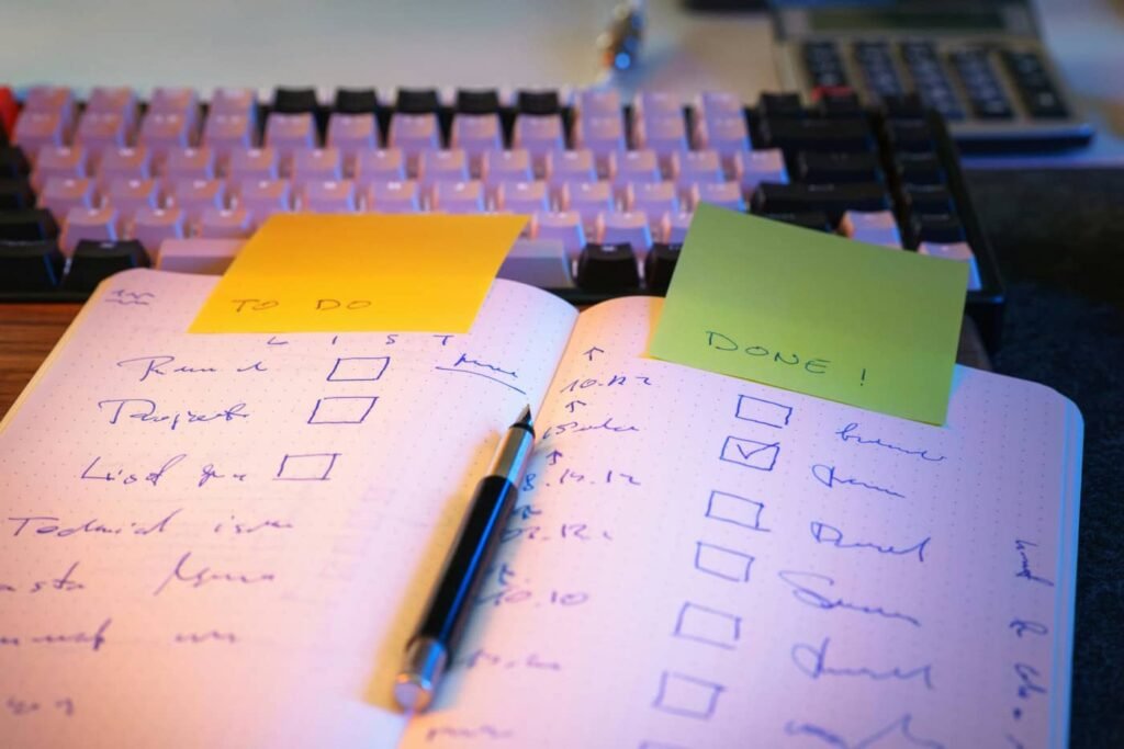 Otwarty notes z odhaczoną listą zadań i napisem "DONE" na zielonej kartce – utrzymywanie nawyków w pracy.