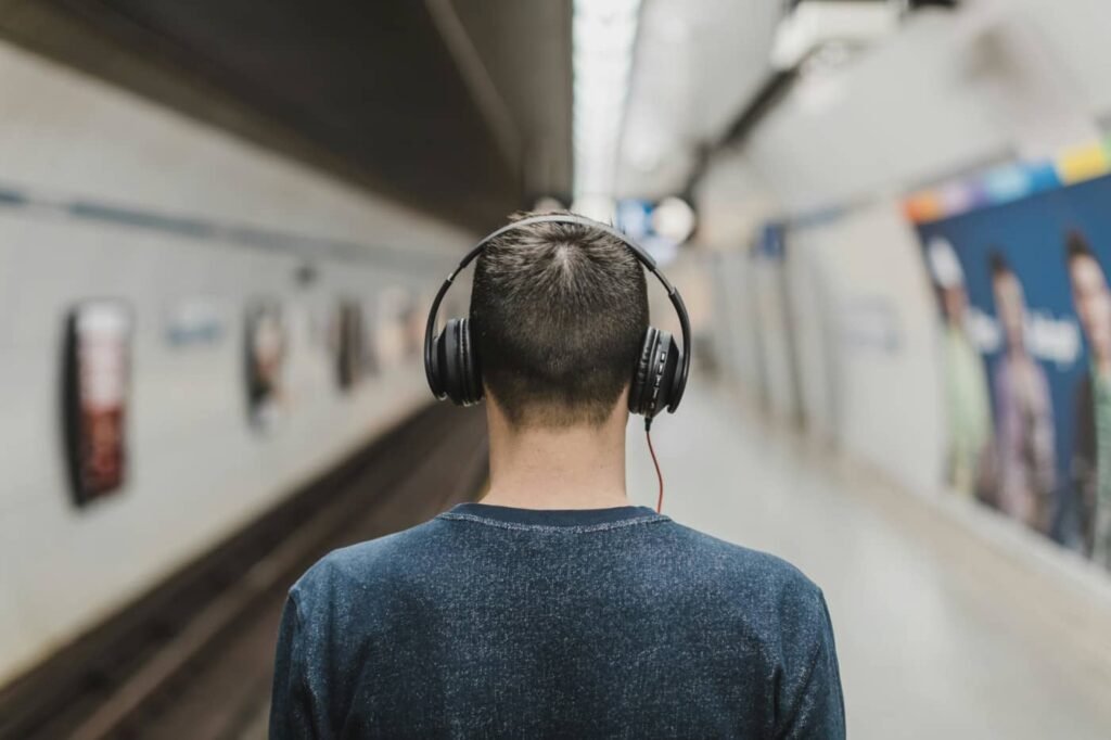 Mężczyzna w słuchawkach na stacji metra – efektywne wykorzystanie czasu w drodze do biura.